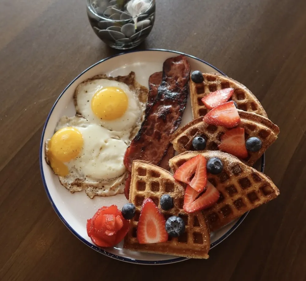 Breakfast platter with two eggs, turkey bacon and waffles with berries